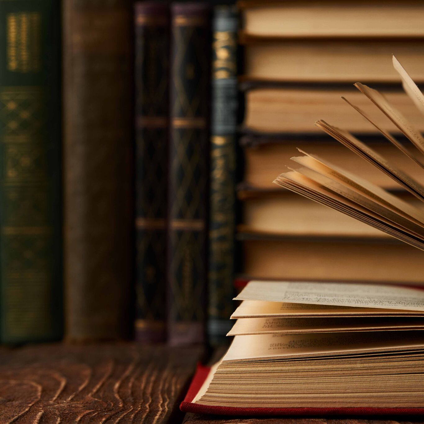 Close up of books with one on table with pages being flicked through.